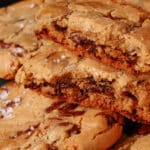 A plate of huge chocolate dipped gluten free jacques torres chocolate chip cookies sprinkled with sea salt.