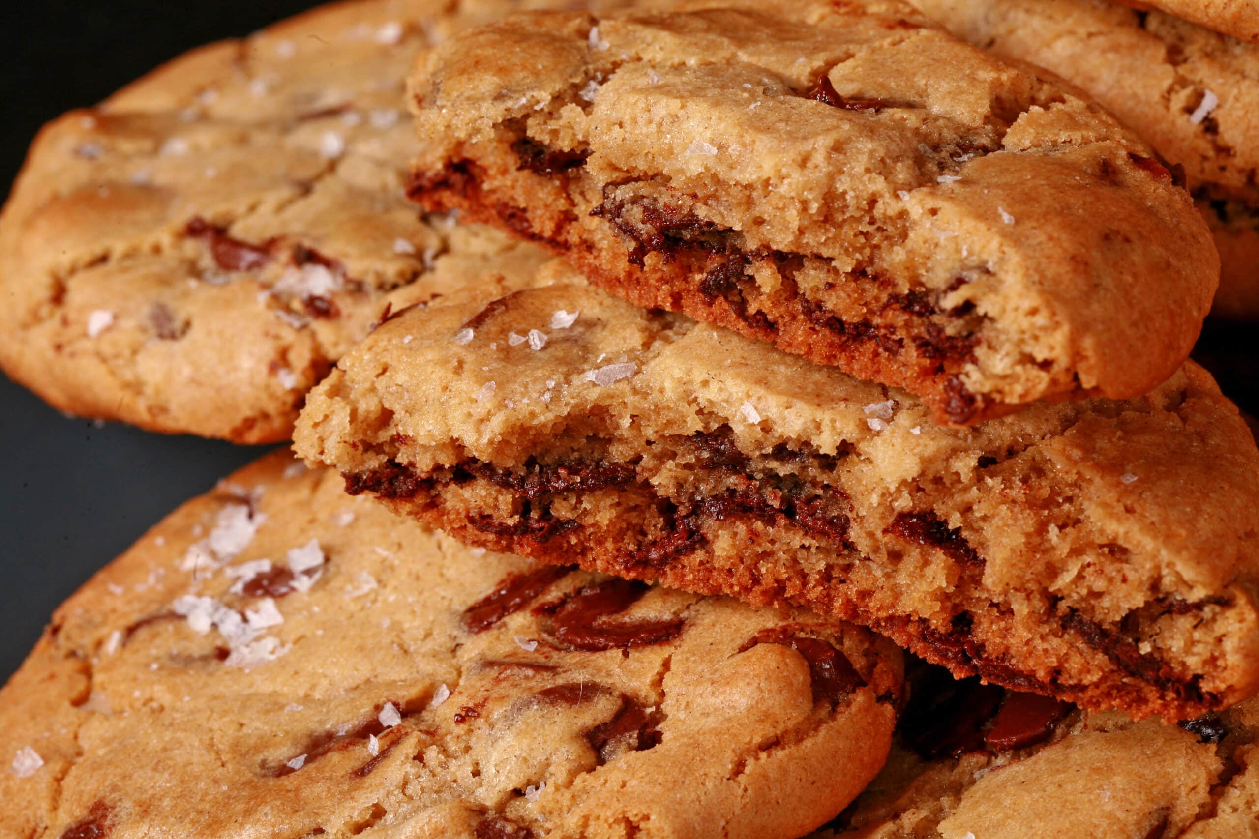 A plate of huge chocolate dipped gluten free jacques torres chocolate chip cookies sprinkled with sea salt.