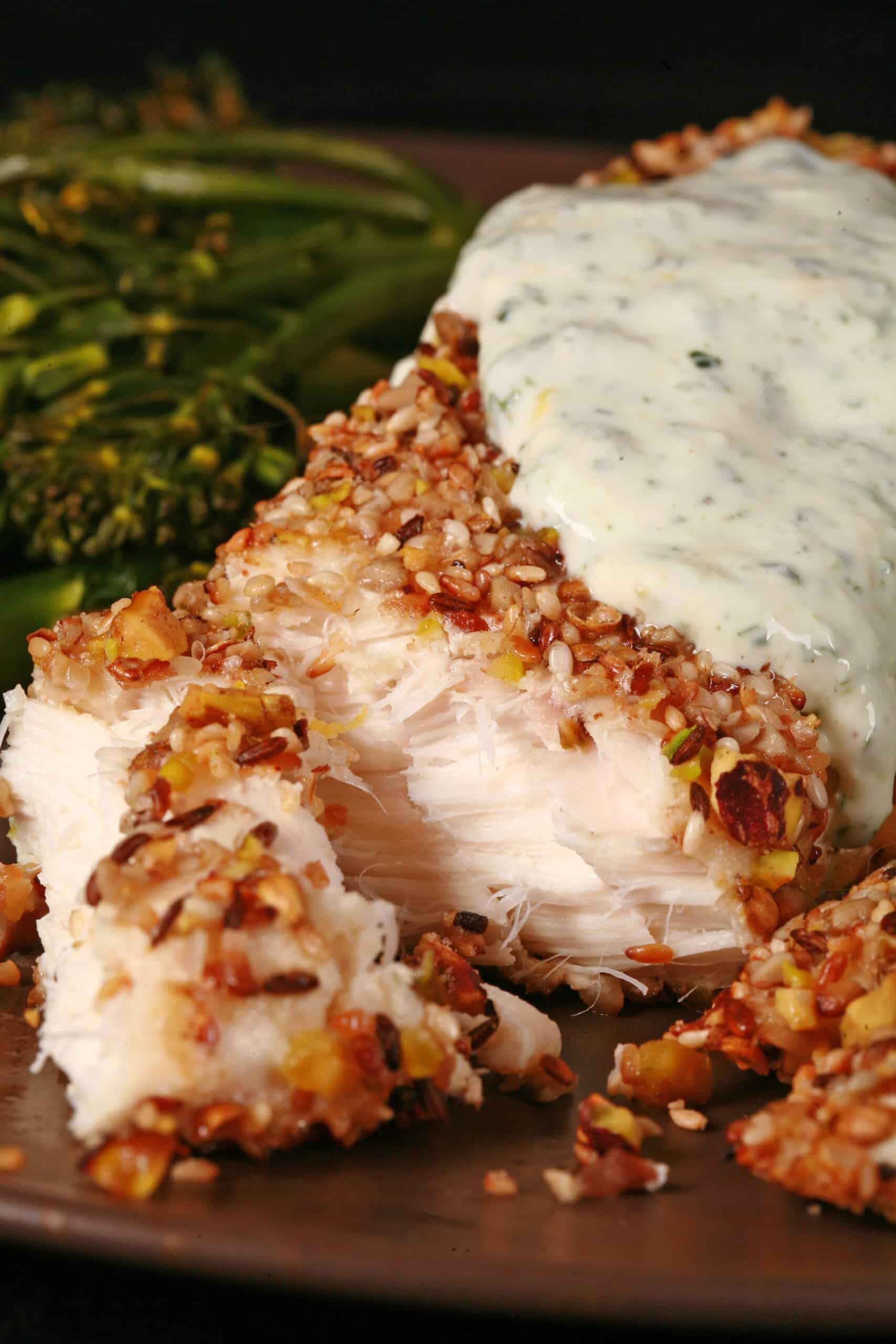 A plate of dukkah crusted halibut filet with lemon mint sauce and broccolini.