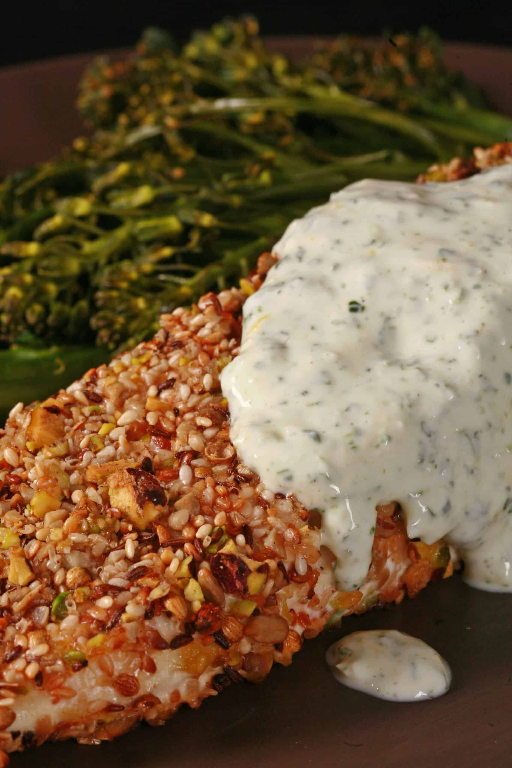 A plate of dukkah crusted halibut filet with lemon mint sauce and broccolini.