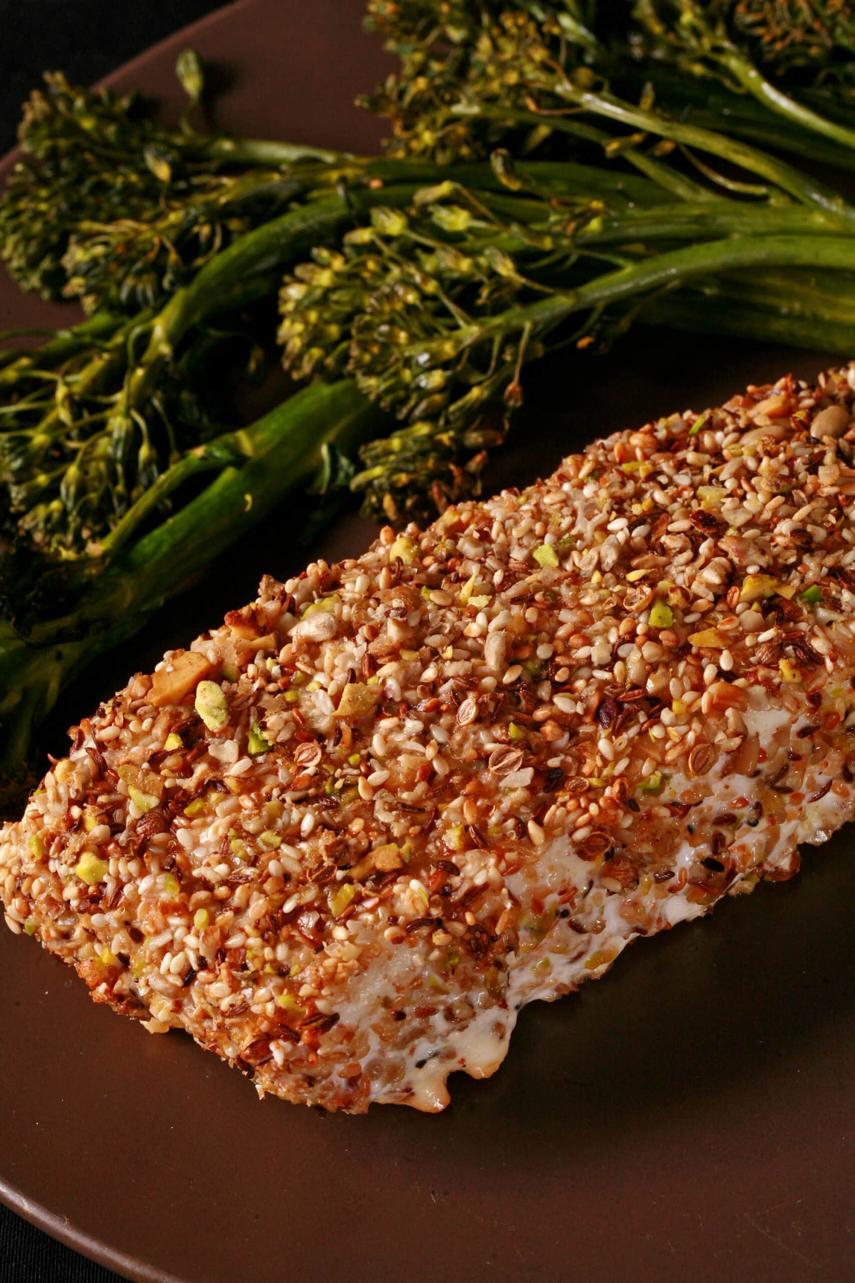 A plate with a dukkah crusted halibut filet and broccolini.