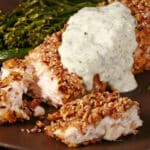 A plate of dukkah crusted halibut filet with lemon mint sauce and broccolini.