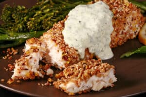 A plate of dukkah crusted halibut filet with lemon mint sauce and broccolini.
