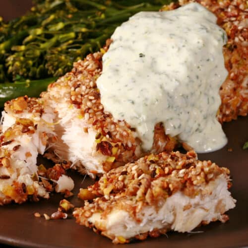 A plate of dukkah crusted halibut filet with lemon mint sauce and broccolini.