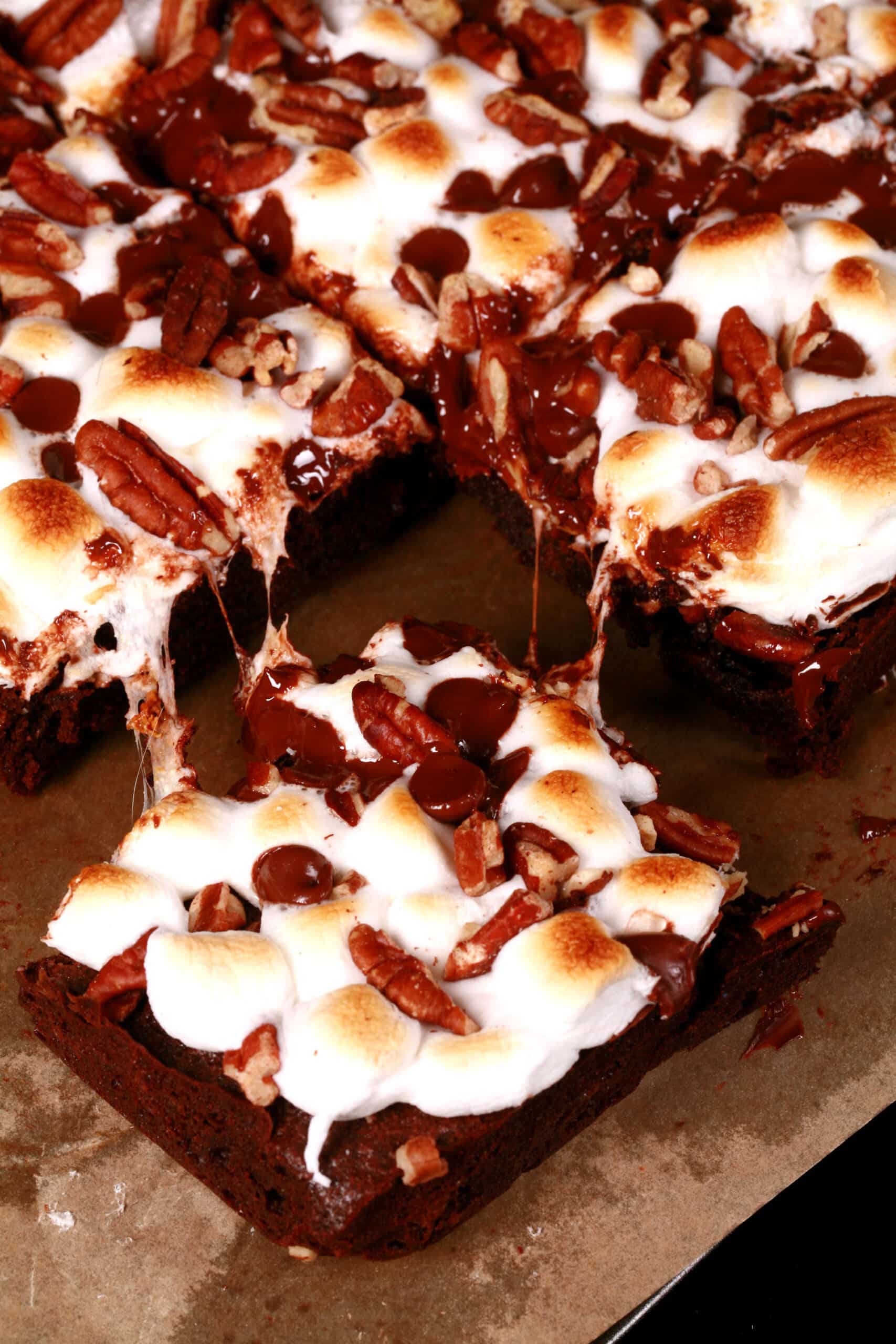 A plate of gluten-free rocky road brownies, topped with toasted mini marshmallows, pecans, and chocolate chips.