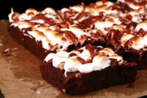 A plate of gluten-free rocky road brownies, topped with toasted mini marshmallows, pecans, and chocolate chips.