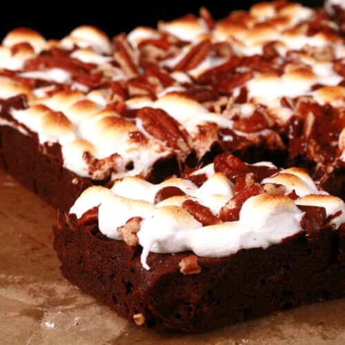 A plate of gluten-free rocky road brownies, topped with toasted mini marshmallows, pecans, and chocolate chips.