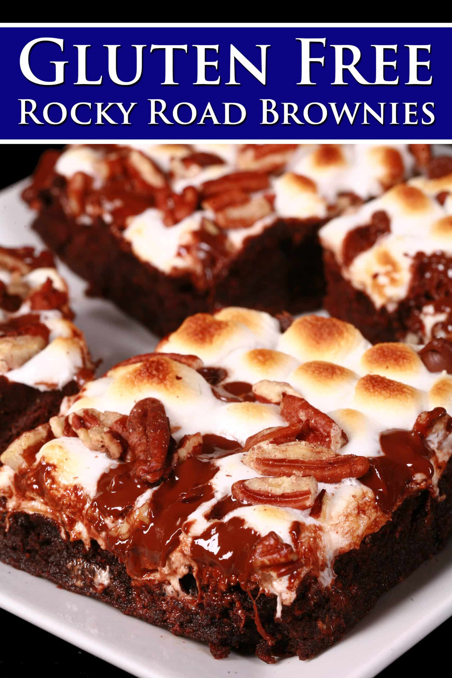 A plate of gluten-free rocky road brownies, topped with toasted mini marshmallows, pecans, and chocolate chips.  Overlaid text says Gluten free rocky road brownies.