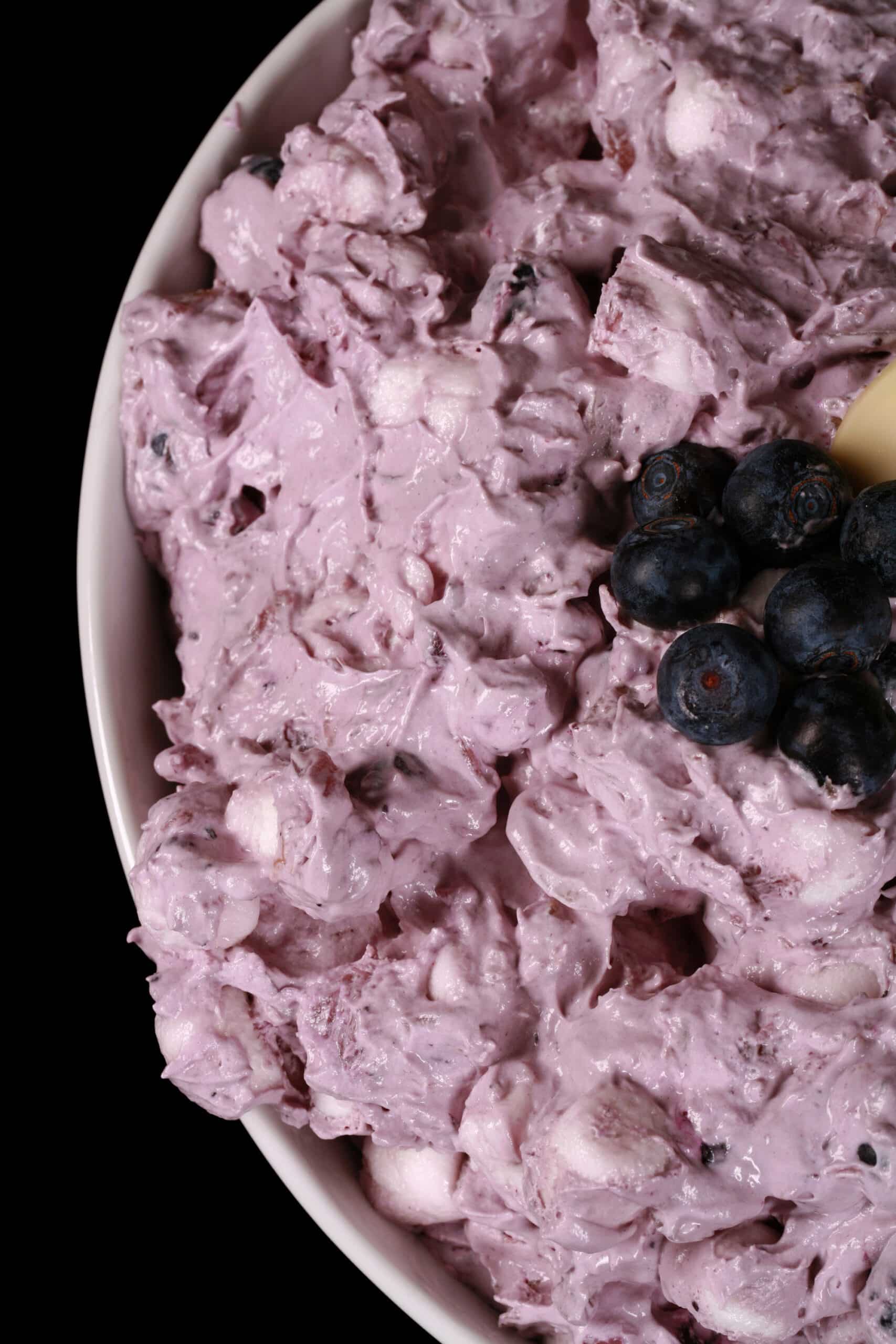 A bowl of blueberry fluff salad with mini marshmallows, almonds, and crushed pineapple.