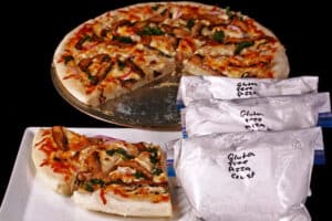 Several freezer bags of homemade gluten-free pizza dough mix, with baked pizza on a plate.