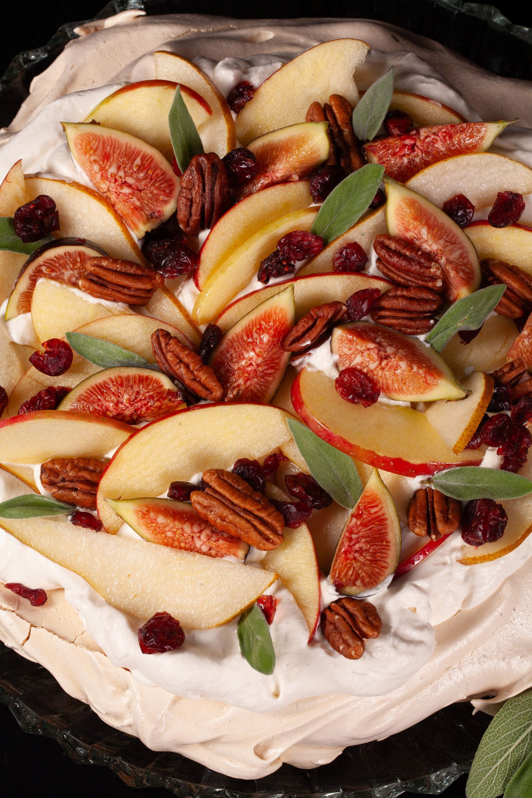 An Autumn pavlova with maple meringue base, maple syrup whipped cream, apples, pears, figs, pecans, dried cranberries, and sage leaves.