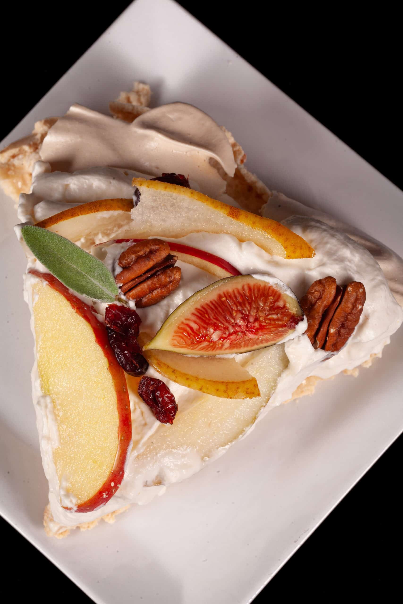 A fall pavlova with maple meringue base, maple syrup whipped cream, apples, pears, figs, pecans, dried cranberries, and sage leaves.