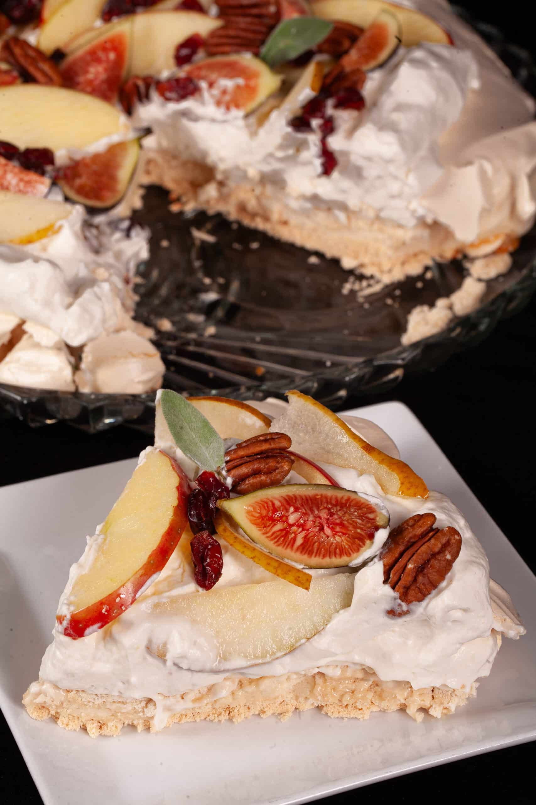 An Autumn pavlova with maple meringue base, maple syrup whipped cream, apples, pears, figs, pecans, dried cranberries, and sage leaves.