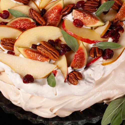 An Autumn pavlova with maple meringue base, maple syrup whipped cream, apples, pears, figs, pecans, dried cranberries, and sage leaves.