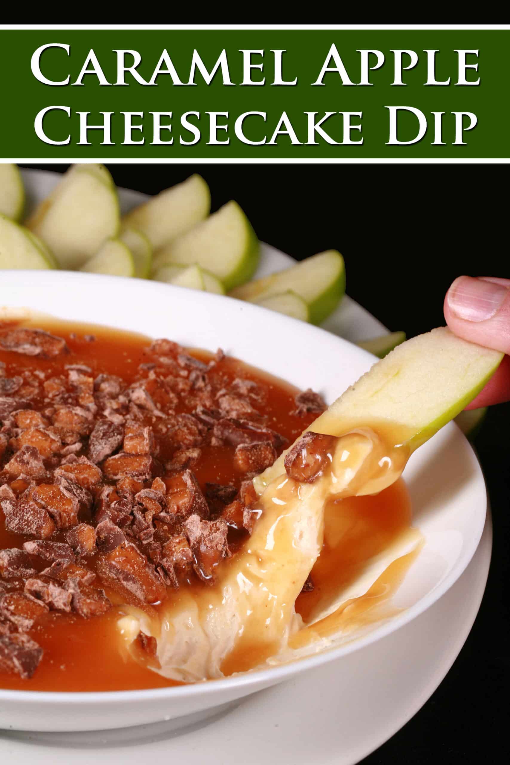 A bowl of cream cheese caramel apple dip, with caramel sauce and chopped Skor bars on top, and sliced granny smith apples behind it. Overlaid text says caramel apple cheesecake dip.