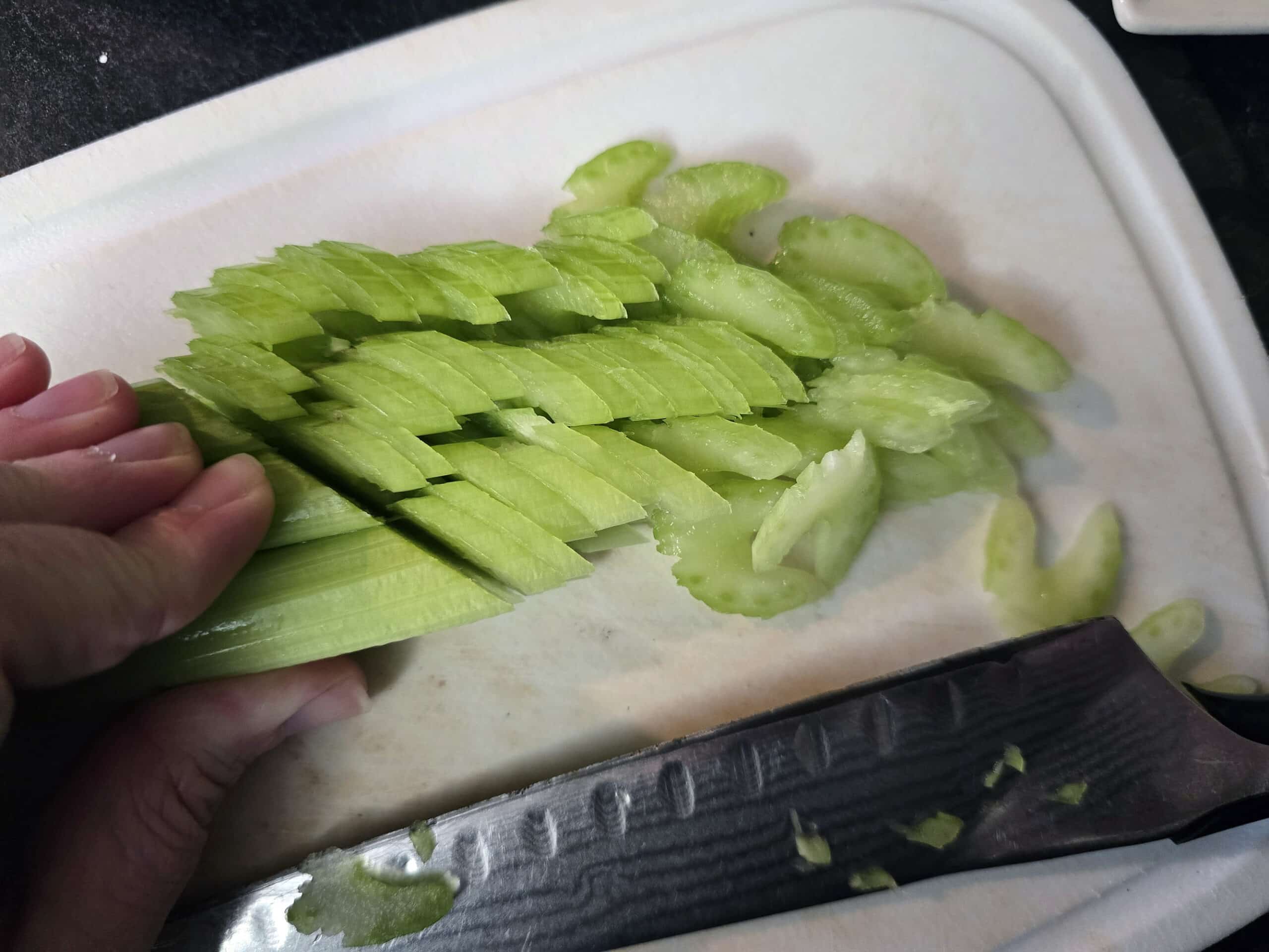 3 celery stalks being sliced on the diagonal, producing pieces that look like Star Trek insignias.