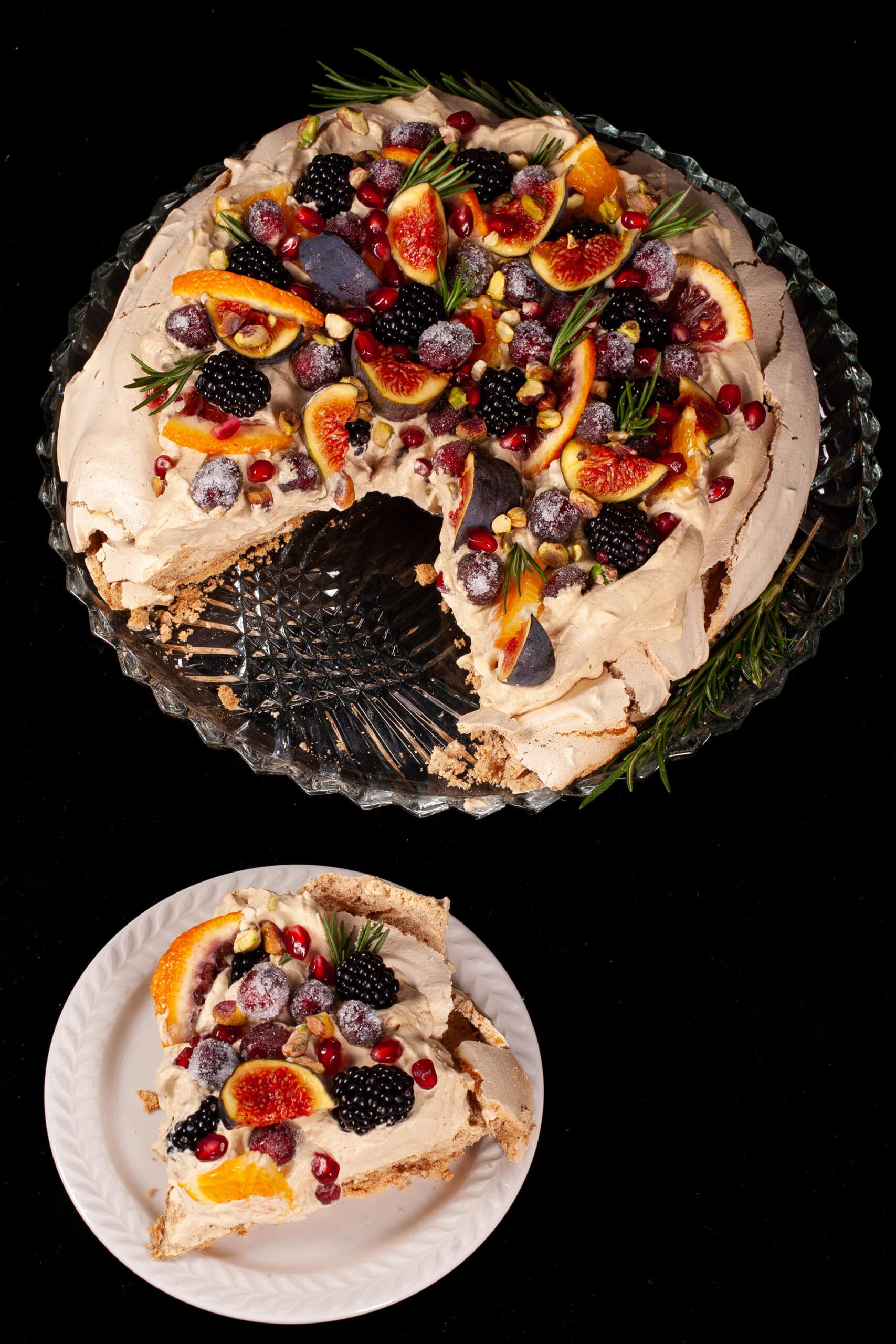 A Christmas pavlova with a gingerbread meringue base, gingerbread flavoured whipped cream, figs, oranges, sugared cranberries, blackberries, pomegranate arils, pistachios, and rosemary.