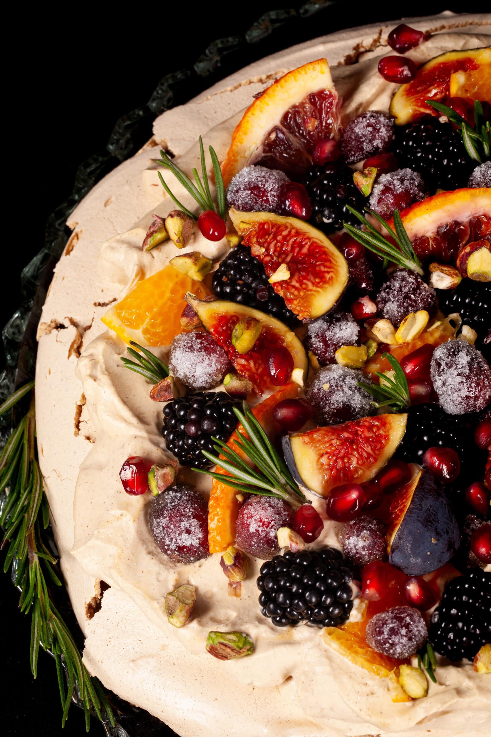 A gingerbread pavlova with a gingerbread meringue base, gingerbread flavoured whipped cream, figs, oranges, sugared cranberries, blackberries, pomegranate arils, pistachios, and rosemary.