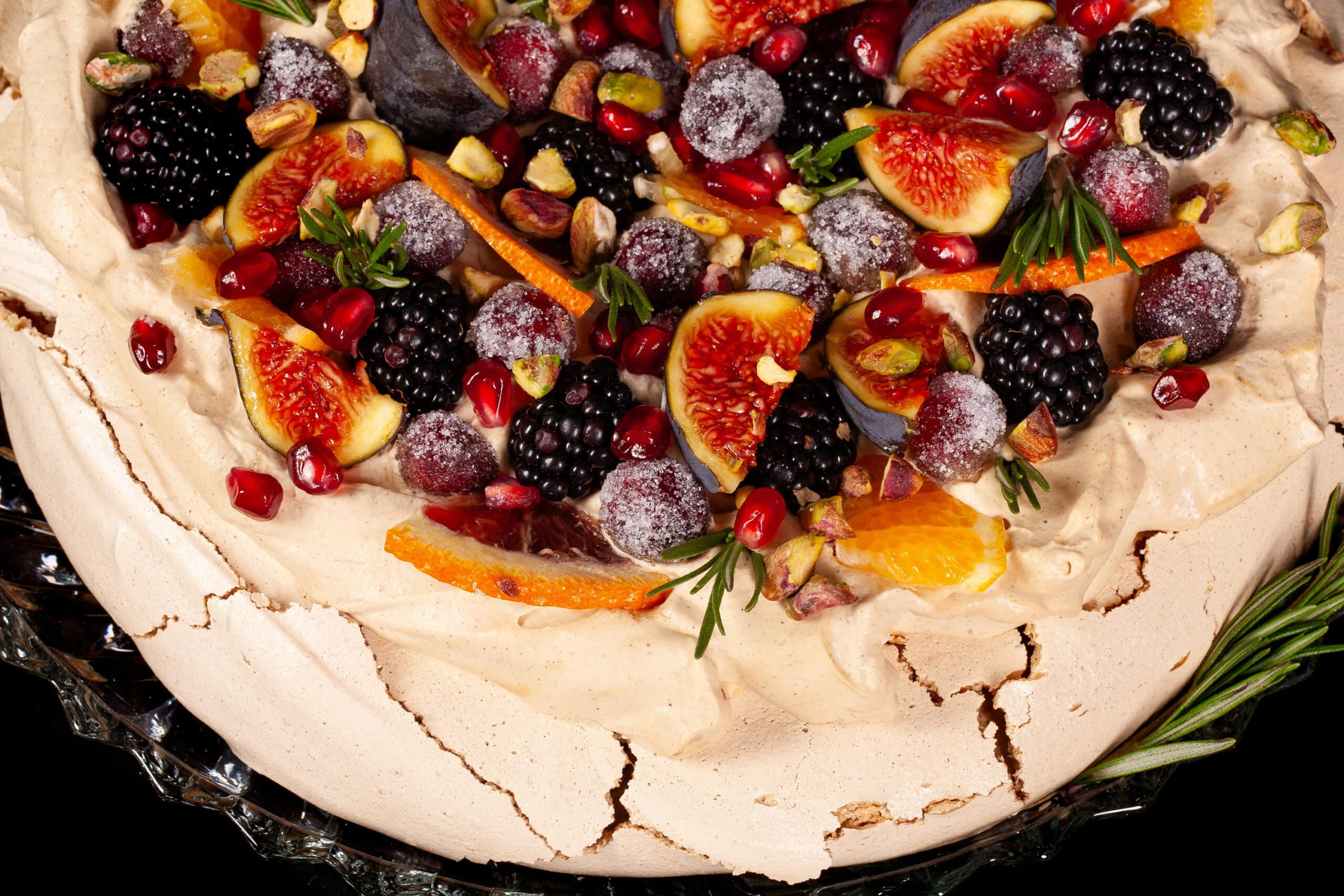 A Christmas pavlova with a gingerbread meringue base, gingerbread flavoured whipped cream, figs, oranges, sugared cranberries, blackberries, pomegranate arils, pistachios, and rosemary.