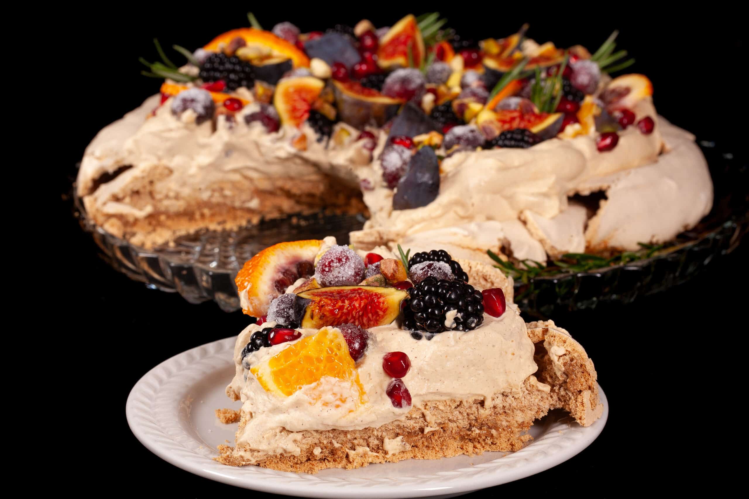 A gingerbread pavlova with a gingerbread meringue base, gingerbread flavoured whipped cream, figs, oranges, sugared cranberries, blackberries, pomegranate arils, pistachios, and rosemary.