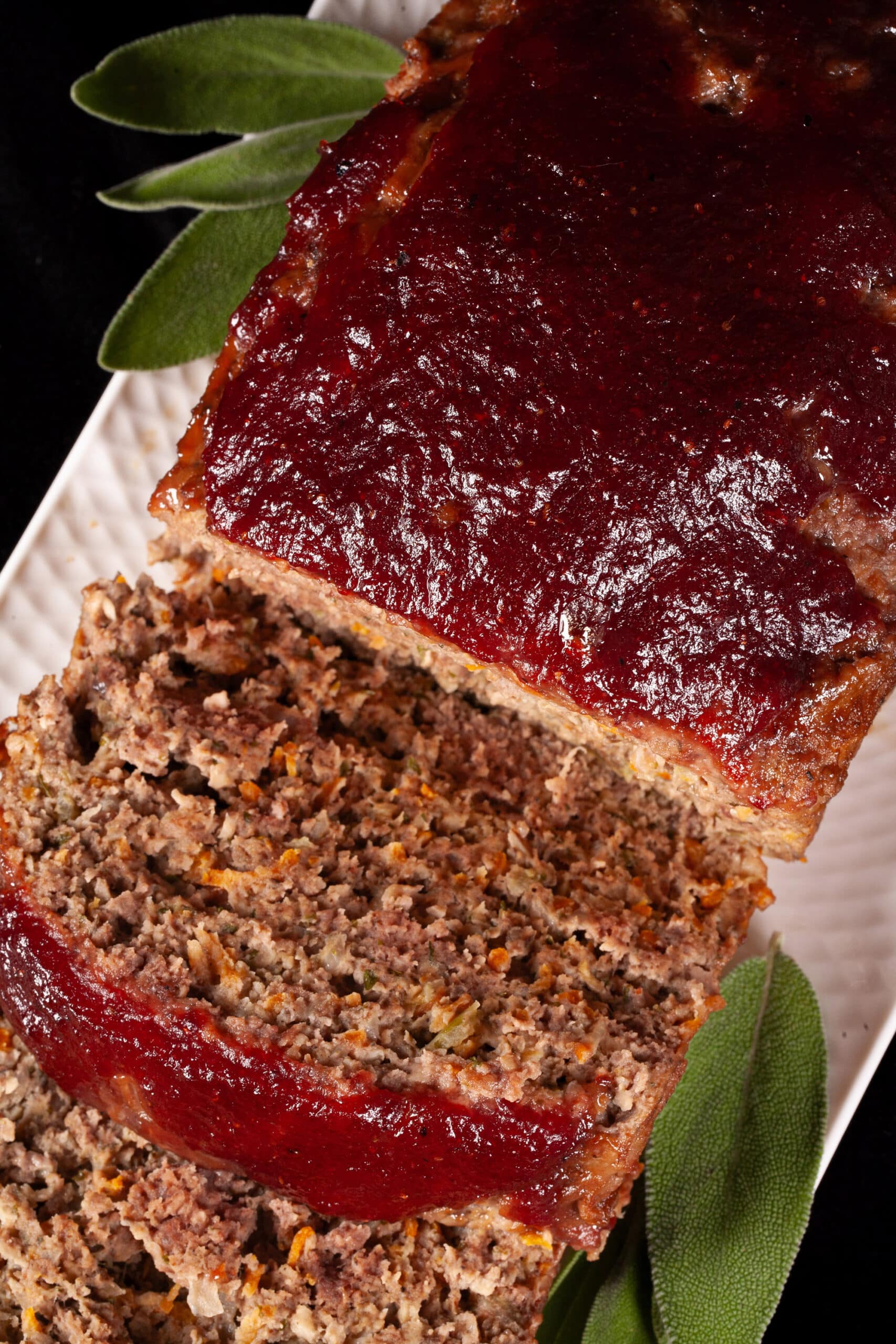 Deer meatloaf with carrots, mushrooms, celery bits, and herbs visible, topped with cranberry ketchup glaze.