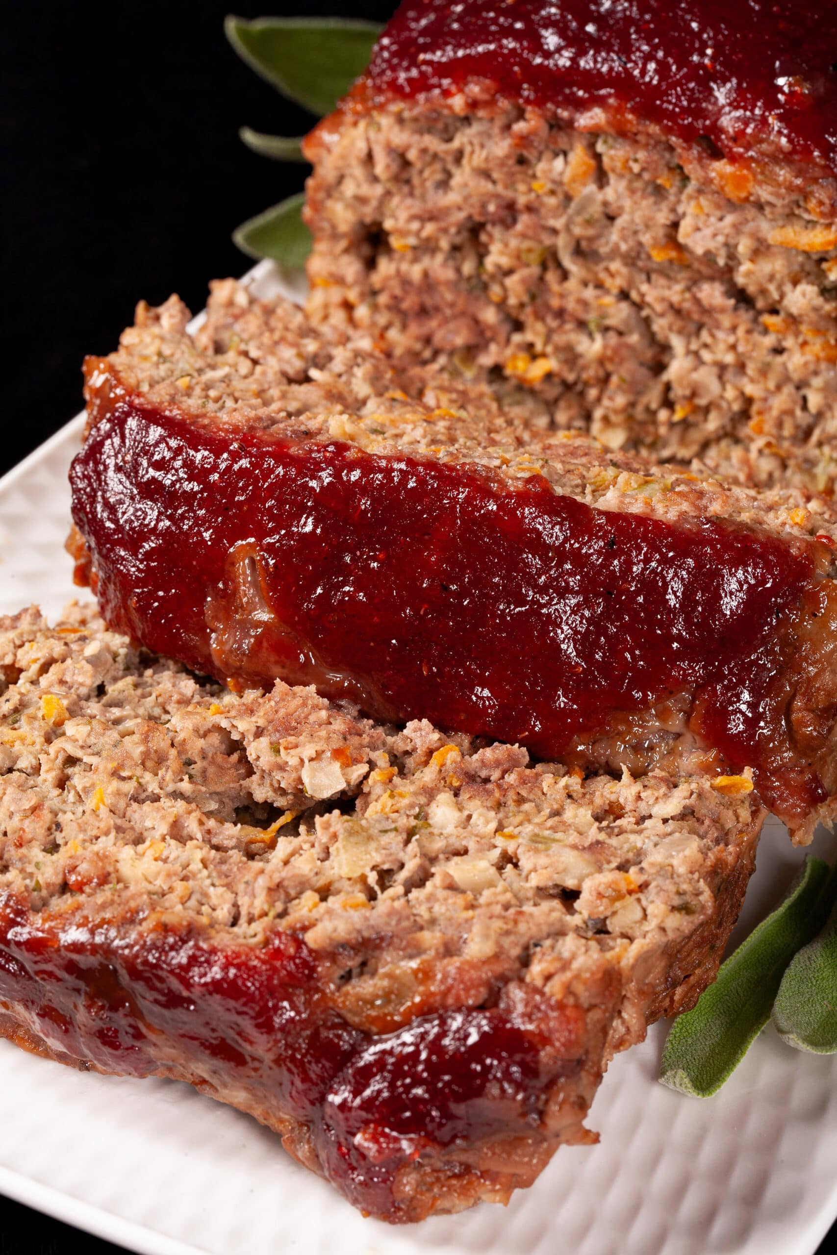 Venison meatloaf with carrots, mushrooms, celery bits, and herbs visible, topped with cranberry ketchup glaze.