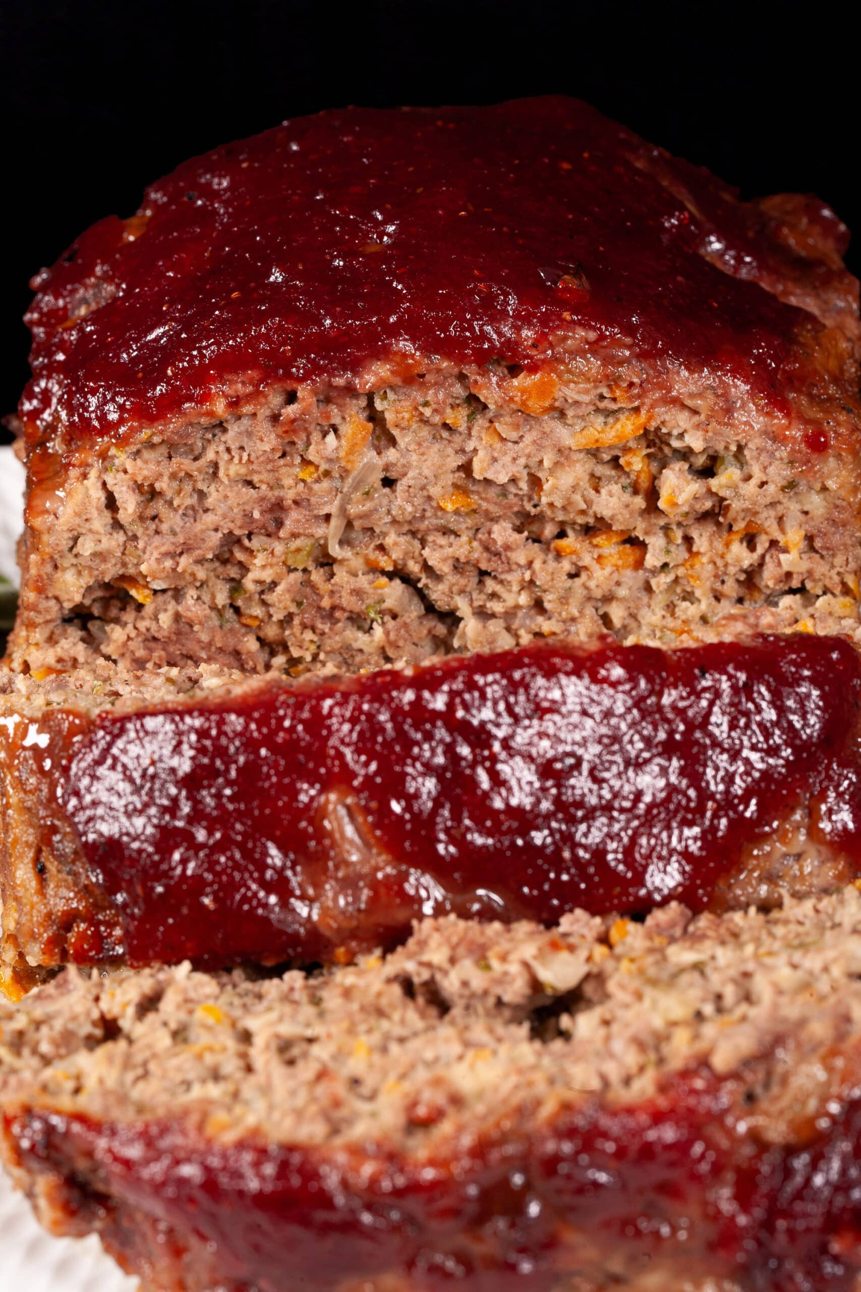 Deer meatloaf with carrots, mushrooms, celery bits, and herbs visible, topped with cranberry ketchup glaze.