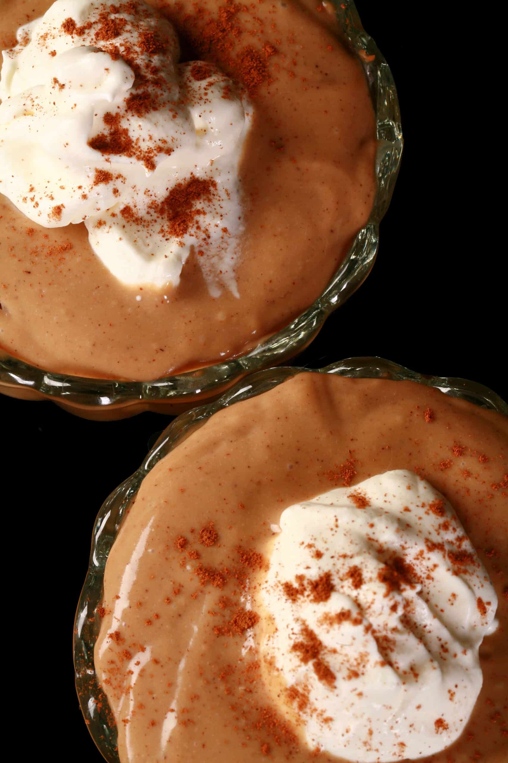 2 bowls of gingerbread pudding, with whipped cream and cinnamon on top.