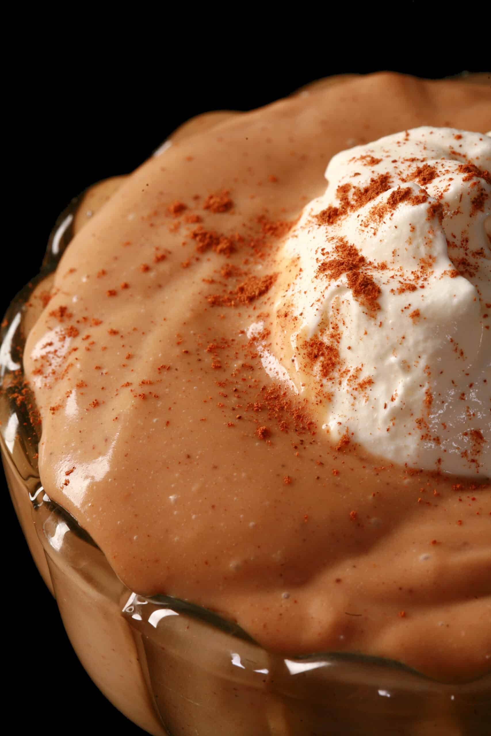 A bowl of homemade gingerbread flavoured pudding, with whipped cream and cinnamon on top.