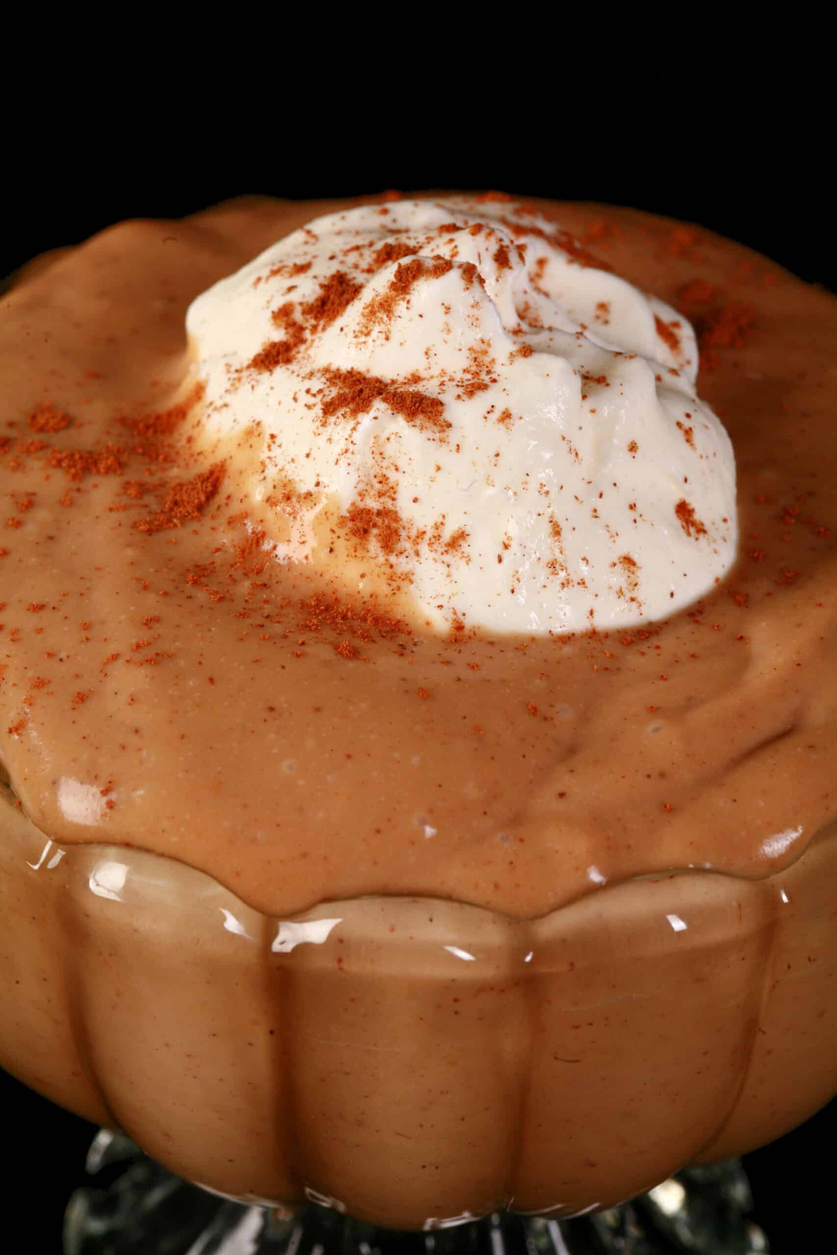 A bowl of homemade gingerbread flavoured pudding, with whipped cream and cinnamon on top.