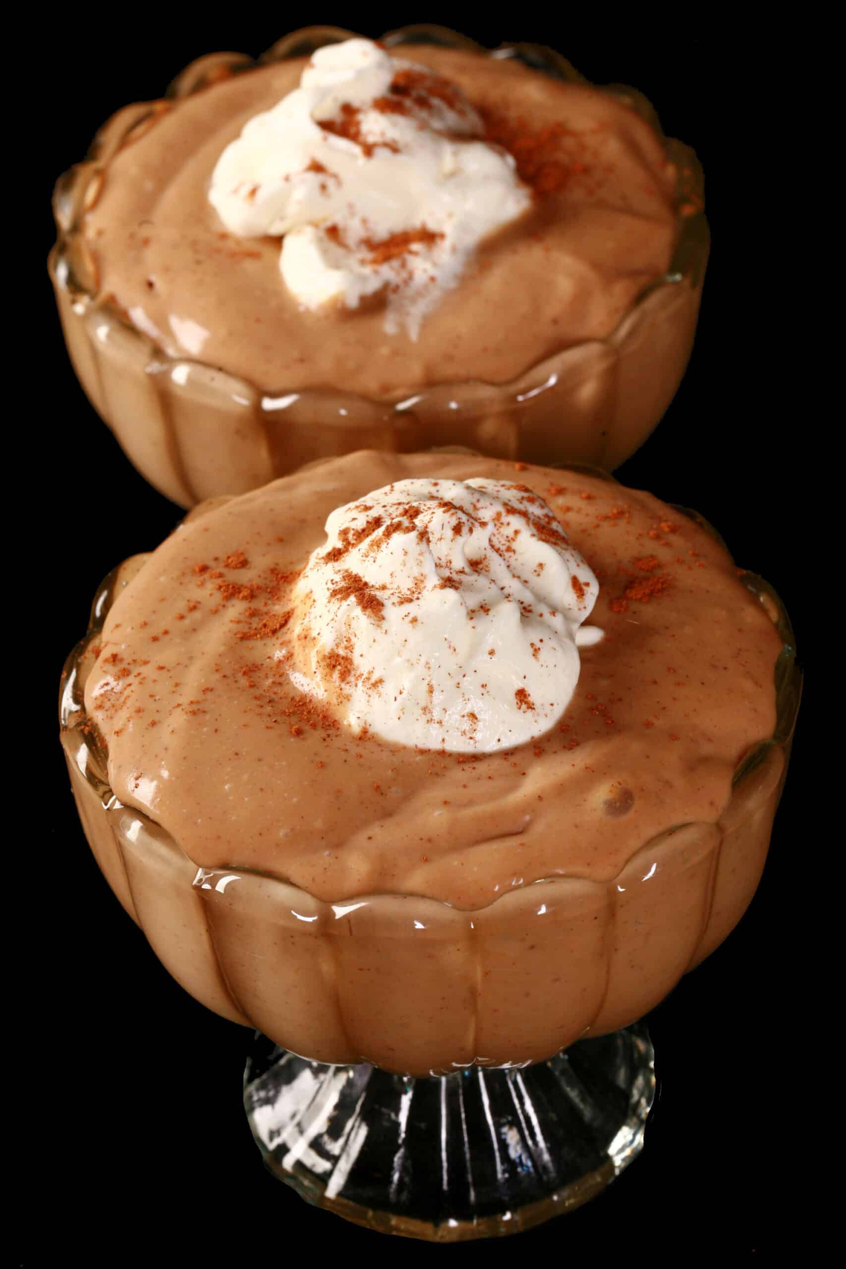 2 bowls of gingerbread pudding, with whipped cream and cinnamon on top.