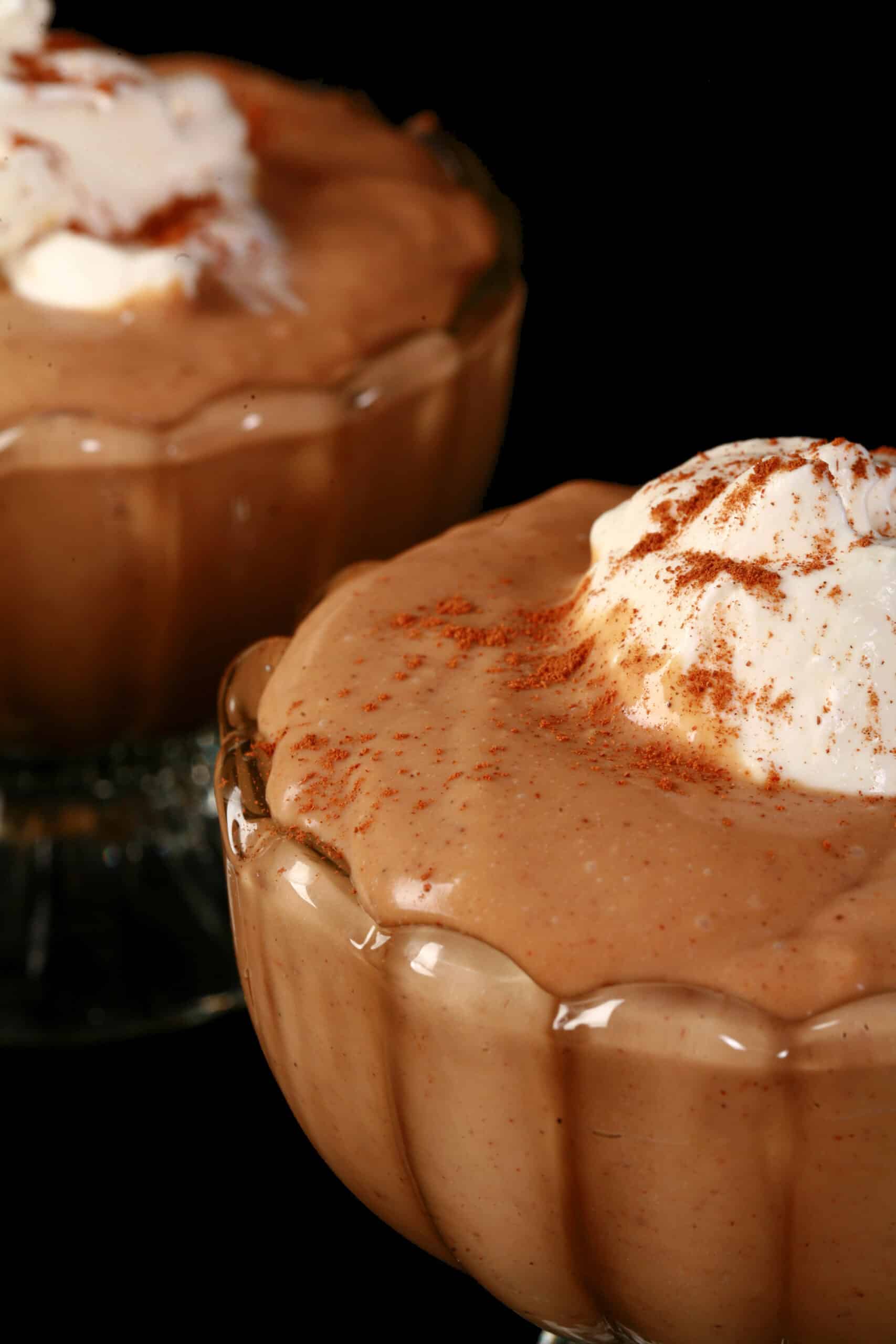 2 bowls of gingerbread pudding, with whipped cream and cinnamon on top.
