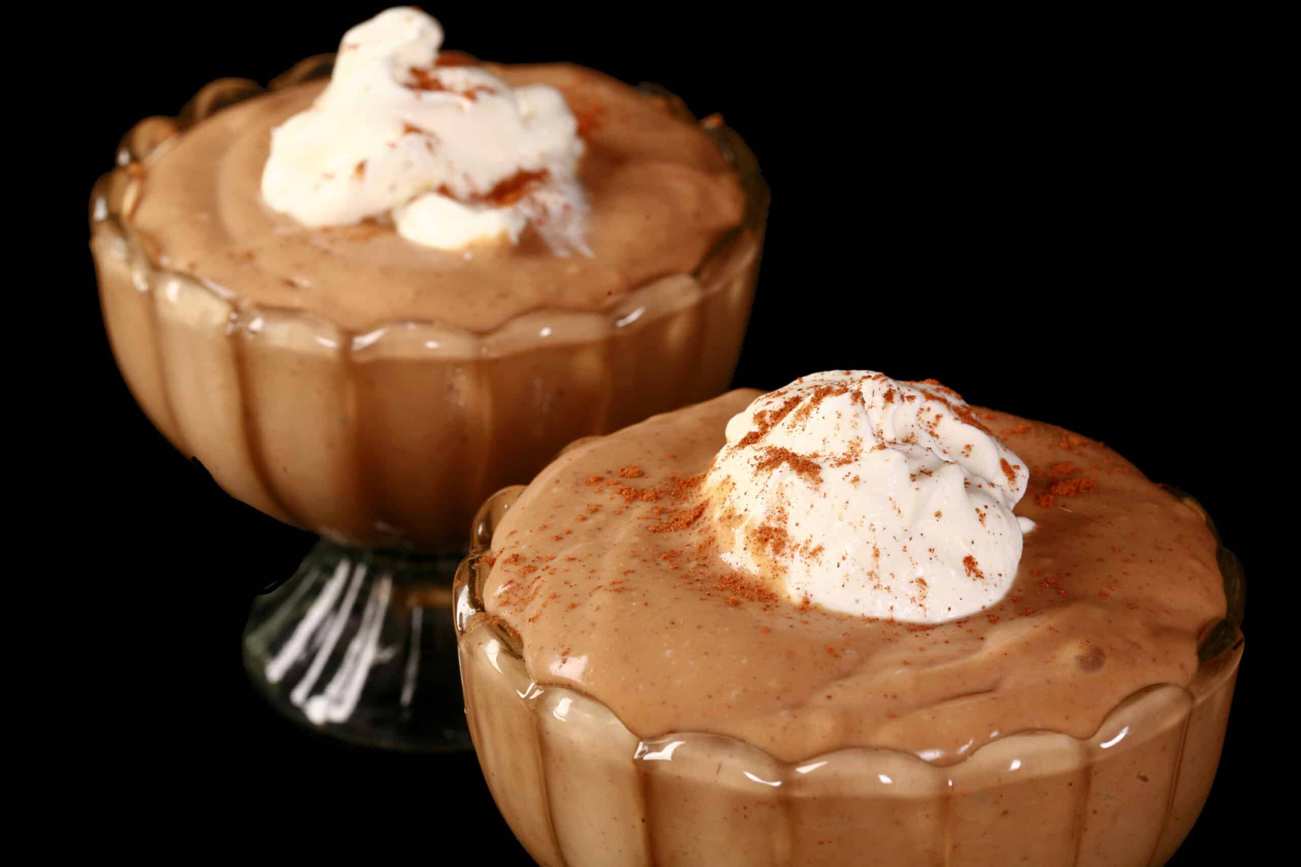 2 bowls of gingerbread pudding, with whipped cream and cinnamon on top.