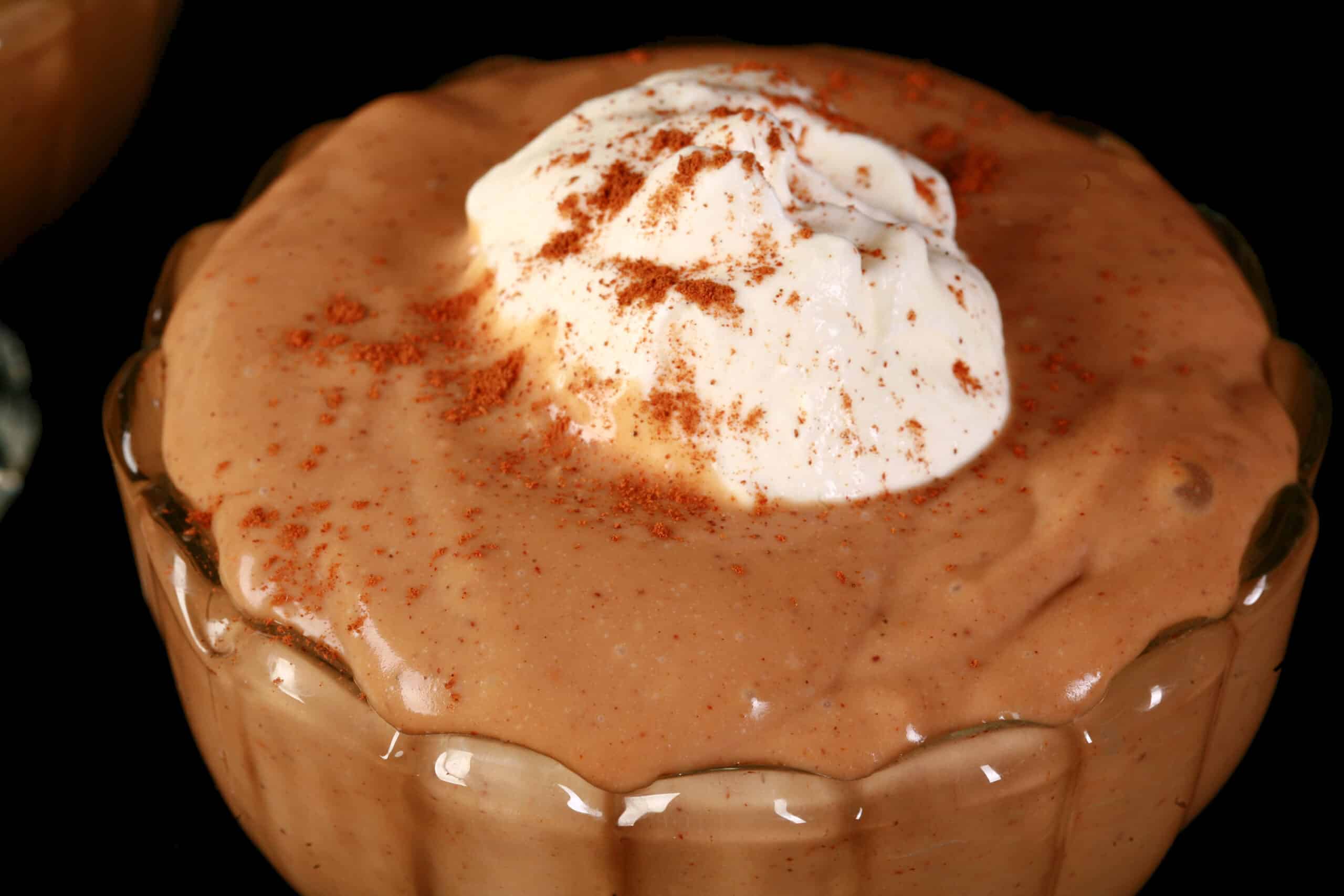 A bowl of homemade gingerbread flavoured pudding, with whipped cream and cinnamon on top.