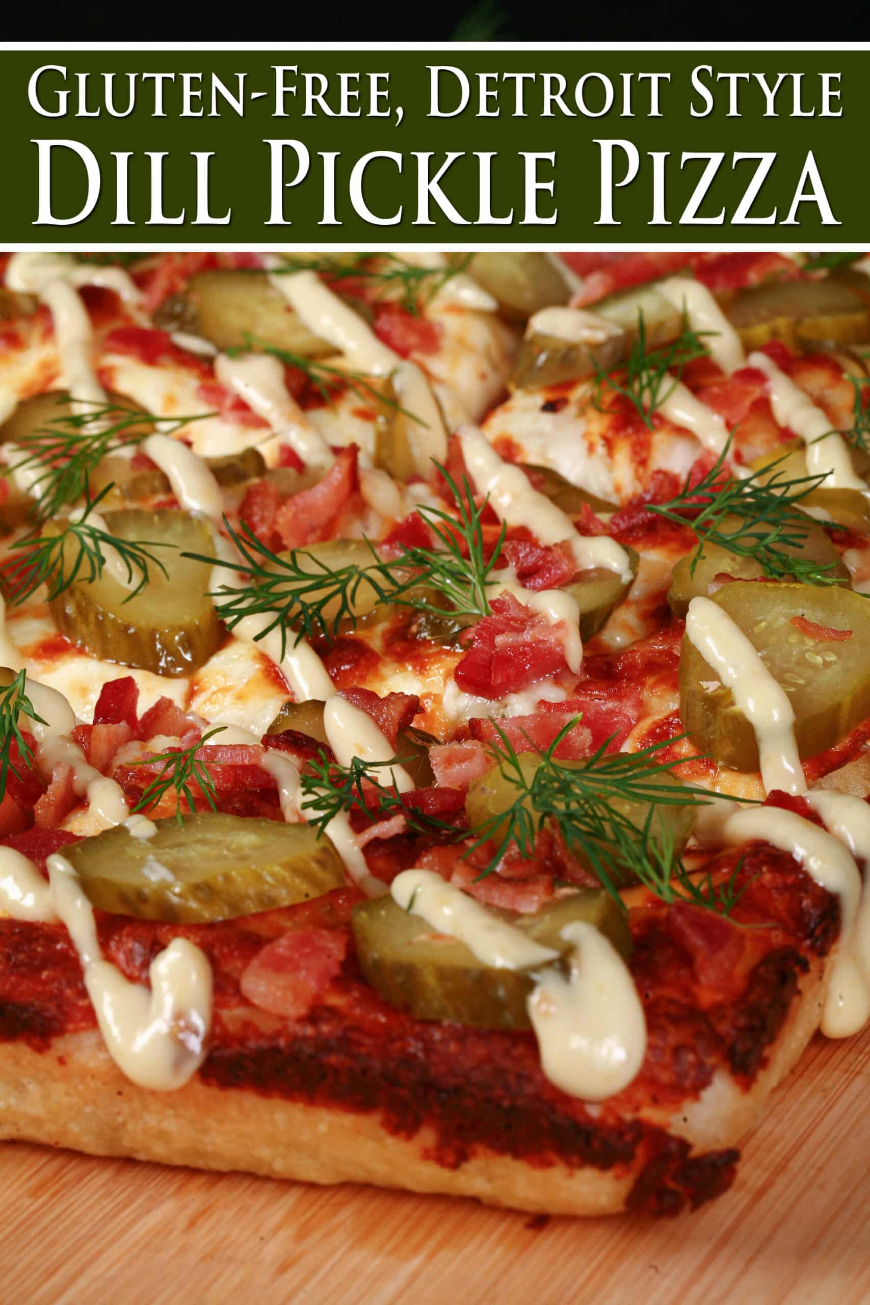 A detroit style gluten free pickle pizza, with dill pickle slices, bacon, fresh dill, and roasted garlic mayonnaise drizzled across it. Overlaid text says gluten free Detroit style dill pickle pizza.